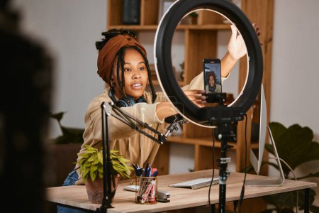 Photo for Communication, phone and influencer live streaming podcast, radio talk show or speaker talk about teen culture. Presenter microphone, black woman setup broadcast or speaking about online student news. - Royalty Free Image
