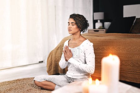 Photo for Remaining one with myself. Full length shot of an attractive young woman sitting and meditating with candles in her living room at home - Royalty Free Image