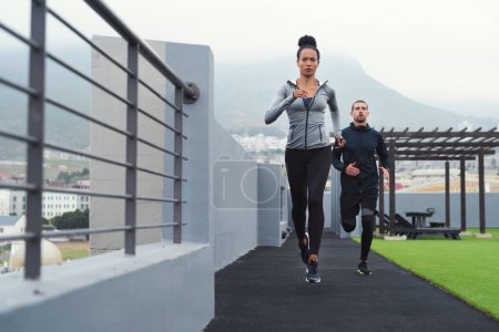 Foto de Nothing will work unless you do. a sporty young man and woman running together outdoors - Imagen libre de derechos