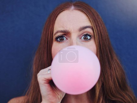 Téléchargez les photos : Closeup portrait, girl and bubblegum by wall, outdoor and urban adventure for funny, comic face and happy. Gen z woman, city and blue background with pink chewing gum, bubble and blowing for fun game. - en image libre de droit