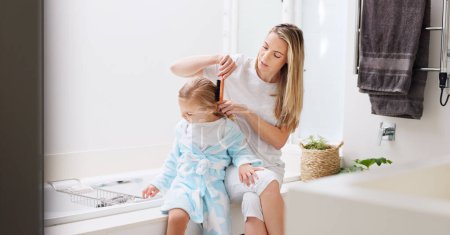 Téléchargez les photos : Hair care, mother and girl in bathroom, with brush and bonding to connect, talking and for fun. Female, lady and daughter or kid doing development, child growth and discussion together at home loving. - en image libre de droit