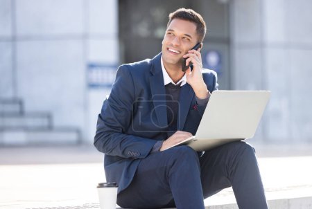 Foto de Thinking, phone call or business man with laptop for internet research, communication or networking. Happy, smile or manager in London street on 5g smartphone for social network, web or blog review. - Imagen libre de derechos