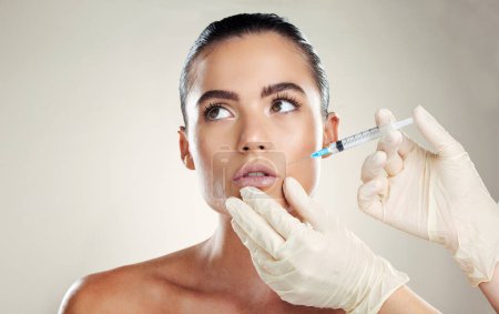 Skincare, aesthetic beauty and woman with injection in lips from healthcare professional, anti aging treatment in studio. Collagen, mouth and model with facial lip filler syringe on white background