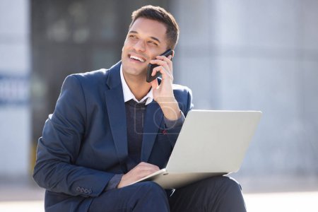 Foto de Happy, phone call or business man with laptop for internet research, communication or networking. Thinking, smile or manager in London street on 5g smartphone for social network, web or blog review. - Imagen libre de derechos