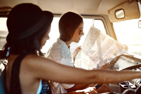 Photo for Pick some place new and go there. two friends reading a map on their road trip - Royalty Free Image