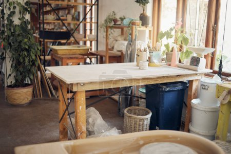 Foto de Creative, art and pottery with empty room of workshop for design, manufacturing and small business. Ceramics, interior and production with table in studio of for painting, inspiration and retail. - Imagen libre de derechos