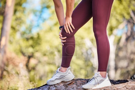 Foto de Knee injury, woman runner and nature park path for fitness, health or rest by trees to massage legs. Outdoor training, running and relax in woods for joint pain emergency, anatomy problem or workout. - Imagen libre de derechos
