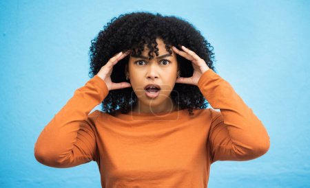 Wow, surprise and portrait with a black woman in shock standing on a blue background in studio. Omg, confused and face with an attractive young female looking shocked or surprised indoor.