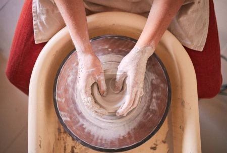Foto de Creative, pottery and design with hands of woman in workshop studio for molding, ceramics and art. Clay, sculpture and manufacturing with girl artisan and wheel for crafting, handmade and hobby. - Imagen libre de derechos