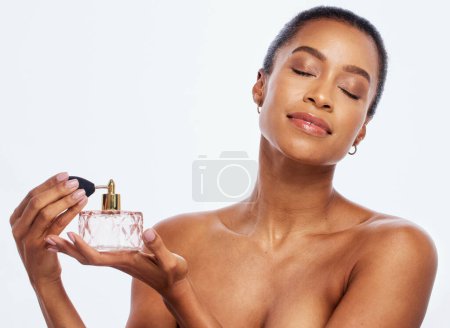 Foto de Fragrance, spray and bottle with black woman in studio for beauty, skincare and cosmetics. Perfume, face and model spraying body product, parfume and makeup for smell, essence and aesthetic mockup. - Imagen libre de derechos