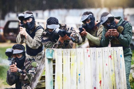 Téléchargez les photos : Paintball, gun or team play in a shooting game together on a fun battlefield on holiday. Men on a mission, fitness or players aim with military weapons gear for survival in an outdoor competition. - en image libre de droit