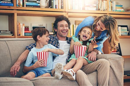 Téléchargez les photos : Movie night - The perfect family friendly activity. a happy family watching movies on the sofa at home - en image libre de droit