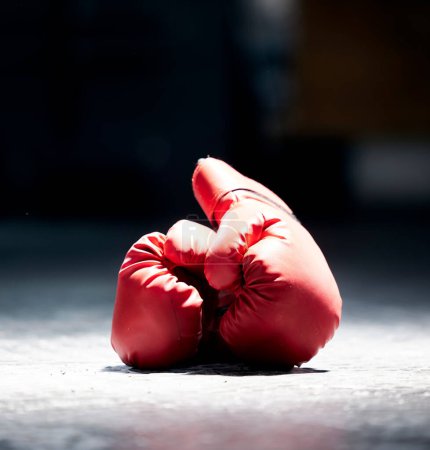 Photo for Boxing gloves, floor and sports on a dark background in studio for health, competition or exercise. Fitness, leather and protective sportswear for a boxer or athlete in competitive fighting. - Royalty Free Image