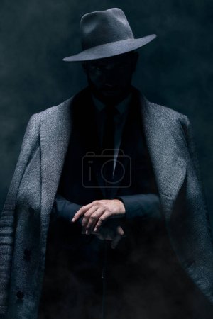 Foto de Mafia, fashion and mystery man in a suit isolated on a dark background in a studio. Business, vintage and stylish secret businessman for crime investigation, spy work and agent on a backdrop. - Imagen libre de derechos