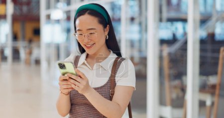 Téléchargez les photos : Phone, mall and Asian woman typing, social media or messaging. Technology, coffee and happy female with mobile smartphone for networking, internet browsing or web scrolling alone at shopping mall - en image libre de droit