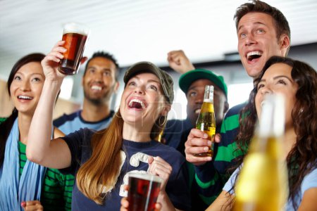 Photo for Watching their favourite team win. A group of excited friends cheering on their favourite team at the bar - Royalty Free Image