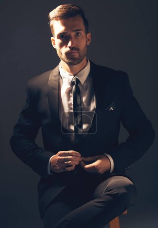 Businessman, suit and portrait in dark studio for corporate fashion, design or professional aesthetic. Young executive leader, model and focus for vision, entrepreneur mindset or tattoo by background.