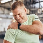 Shoulder pain, fitness and bodybuilder man in gym for training, workout and challenge exercise with medical risk. Injury, muscle and strong person or athlete with sports burnout, arm or arthritis.