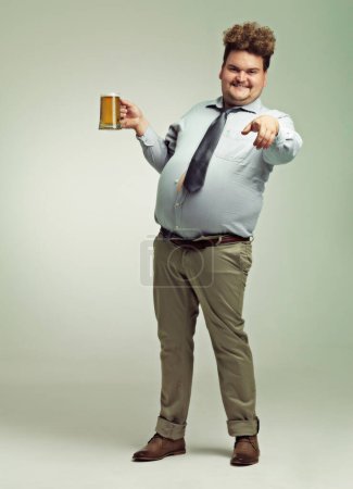 Photo for Ive been waiting for you. an overweight man pointing at the camera while holding a pint of beer - Royalty Free Image