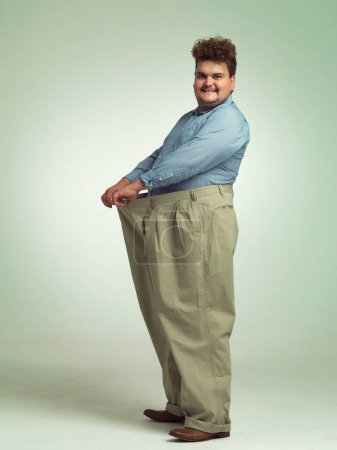Photo for Wearing my big boy pants. an overweight man wearing a pair of oversized pants looking pleased - Royalty Free Image