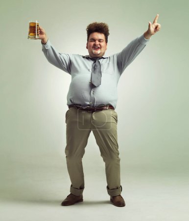 Téléchargez les photos : Time to party. an overweight man celebrating while holding a pint of beer - en image libre de droit