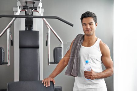 Photo for Committed to staying fit and healthy. A young ethnic man standing next to an exercise machine at the gym - Royalty Free Image