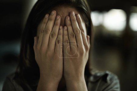 Photo for Im so afraid...A young woman looking anxious and fearful with her hands over her eyes - Royalty Free Image