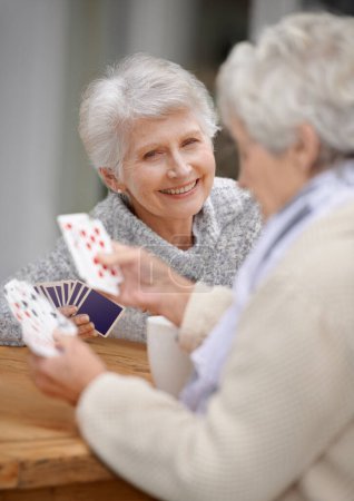 Téléchargez les photos : Helping the time pass with card games. Two senior women playing cards together - en image libre de droit