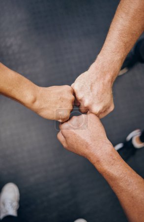 Photo for Hands, motivation and collaboration with people in the gym from above for health, fitness or solidarity. Teamwork, training and partnership with an athelte group doing a fist bump together for unity. - Royalty Free Image
