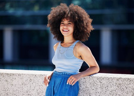 Portrait, mode et ville avec une femme noire en plein air sur un pont, l'air détendu pendant une journée d'été. Rue, style ou urbain et une jeune femme attrayante posant à l'extérieur avec une coiffure afro.