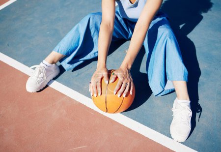 Photo for Basketball, hands and woman on the outdoor court floor with urban fashion for influencer beauty. Sport, model and young person sitting with gen z clothes with sports game equipment in summer. - Royalty Free Image