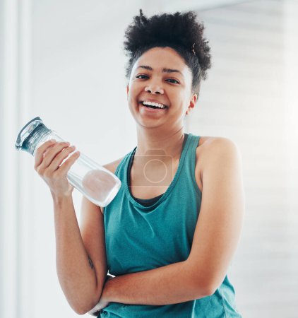 Retrato, fitness y agua con una mujer negra deportiva que se mantiene hidratada durante su ejercicio cardiovascular o de resistencia. Ejercicio, entrenamiento y bienestar con una atleta sosteniendo una botella para hidratación.