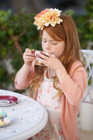 Téléchargez les photos : Tea time in the garden. A cute little girl having a tea party outside - en image libre de droit