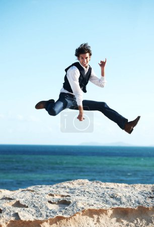 Foto de Qué gran sensación. Feliz joven saltando en el aire con el océano en el fondo - Imagen libre de derechos