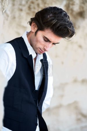 Foto de Alto, oscuro y melancólico. Primer plano de un joven guapo con un chaleco y mirando hacia abajo - Imagen libre de derechos
