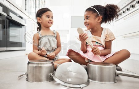 Foto de Girl kids playing house with pots as drums, happy and care free at family home, make believe with music and fun. Noise, metal and children on floor, play date together and fantasy with imagination. - Imagen libre de derechos