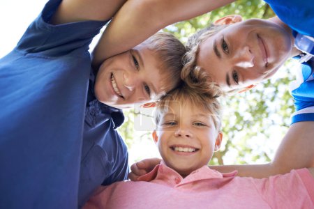 Photo for Theres nothing like having awesome brothers. Three brothers huddling together while playing outdoors in the bright sunshine - Royalty Free Image