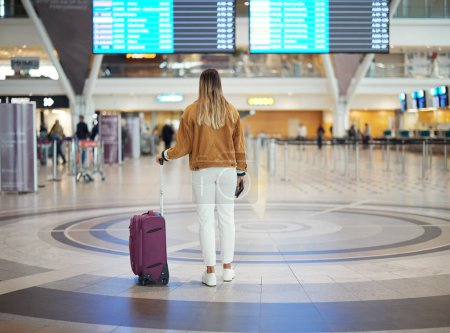 Photo for Woman, airport and luggage checking flight times for travel, vacation or journey with passport in Cape Town. Female traveler standing and waiting ready for departure, boarding plane or immigration. - Royalty Free Image
