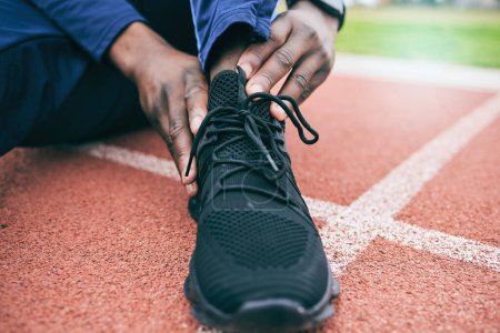 Photo for Sports, feet and man with ankle pain from exercise, workout and marathon training in stadium. Fitness, runner and shoes of athlete with joint strain, injury and arthritis from running on field track. - Royalty Free Image