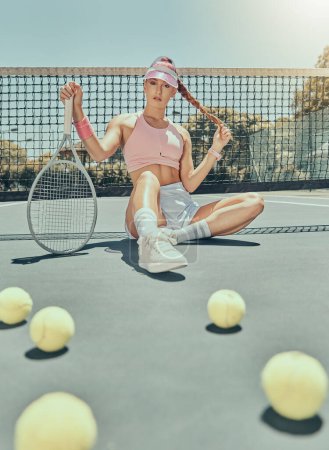Foto de Portrait, tennis sports and woman on court with racket after workout, training or exercise. Fashion, fitness balls or female athlete sitting, resting or relax on stadium outdoors after match or game. - Imagen libre de derechos