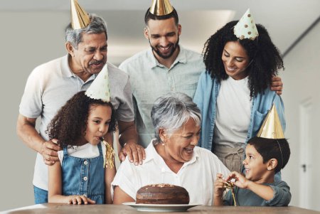 Téléchargez les photos : Joyeux anniversaire, femme âgée et fête de famille à une table avec un gâteau, amour et soins dans une maison. Enfants, parents et grands-parents réunis pour une fête pour célébrer grand-mère excitée avec le dessert. - en image libre de droit