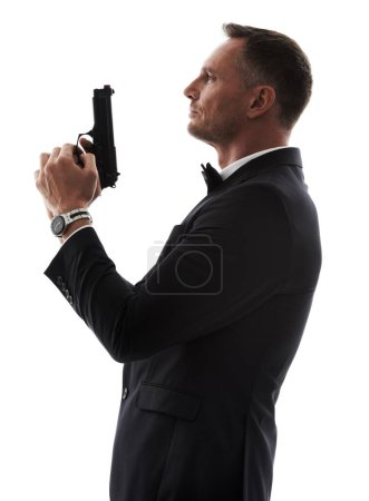Photo for Spy man, profile and gun with suit for undercover mission, justice or espionage by white background. Government agent, detective and weapon in studio with designer tuxedo, secret information and work. - Royalty Free Image