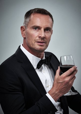 Photo for Tuxedo, red wine and spy man with alcohol in a suit feeling classy with a luxury drink. Gray background, isolated and studio with a model, agent or actor with a glass and rich person with mockup. - Royalty Free Image