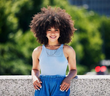 Portrait, fashion and city bridge with a black woman outdoor, looking relaxed during a summer day. Street, style or urban and an attractive young female posing outside with an afro hairstyle.