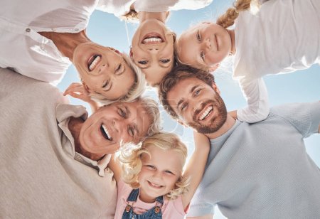 Photo for Happy family, huddle and smile below in trust, community or support together against a blue sky. Portrait of grandparents, parents and children hugging, smiling or bonding for holiday break in nature. - Royalty Free Image