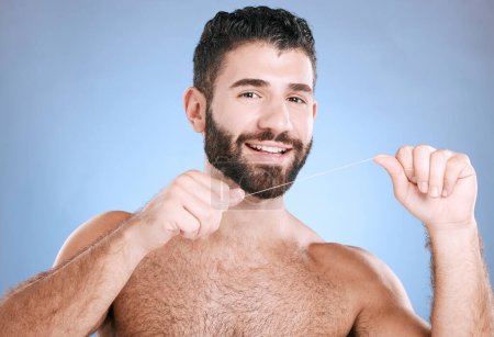 Téléchargez les photos : Flossing, dental and man with cleaning teeth, portrait and healthcare for mouth, face and oral care for hygiene. Grooming, beauty and wellness, fresh breath and gum health isolated on blue background. - en image libre de droit
