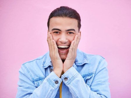 Photo for Man, hands and cheeks for surprise in portrait with happiness, excited and pink wall background. Happy gen z model, wow face and smile for announcement, fashion and news for career, success and goal. - Royalty Free Image