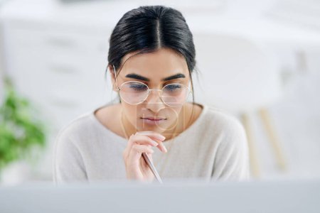 Photo for She pays attention to all the details to her tasks. High angle shot of a young businesswoman looking thoughtful while working on a computer in an office - Royalty Free Image