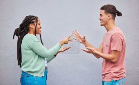 Photo for Couple playing rock, paper, scissors by a wall in the city for game, decision or choice while on holiday. Playful, happy and interracial and woman having fun together in town while on a vacation - Royalty Free Image