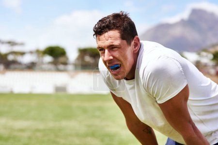 Guard your gums like you guard the ball. a young man wearing a gum guard while playing a game of rugby